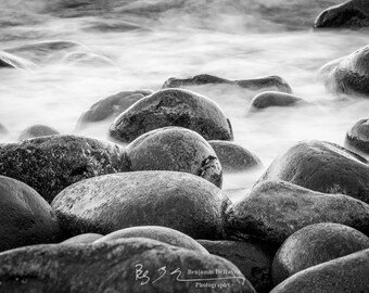 A black and white shot of Boulder Beach in Acadia National Park in Maine. This long exposure makes the Atlantic Ocean waves seem misty.