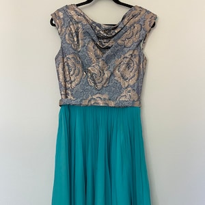 Puede incluir: Un vestido azul turquesa con falda plisada y corpiño floral plateado y dorado.