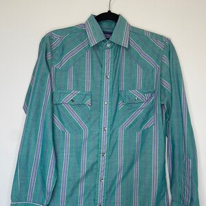 May include: A green and purple striped long-sleeved button-down shirt with two chest pockets and a pointed collar.