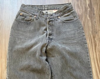 Puede incluir: Un par de pantalones vaqueros de mezclilla gris oscuro con cierre de botón y cinco bolsillos.