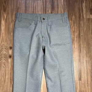 Puede incluir: Un pantalón gris de pierna recta con cierre de botón y trabillas para el cinturón.