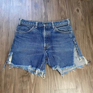 Puede incluir: Pantalones cortos de mezclilla desgastados con bordes deshilachados y cintura alta. Los pantalones cortos tienen un lavado azul claro y están hechos de una tela suave y cómoda.