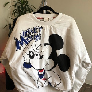 May include: White sweatshirt with a large Mickey Mouse graphic on the front. The graphic is in blue, black, and red. The text "Mickey Mouse" is printed in blue above the graphic.