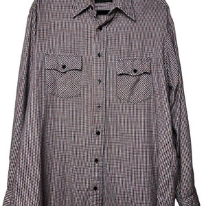 May include: A long-sleeved button-down shirt with a checkered pattern in red, white, and navy blue. The shirt has two chest pockets and a classic collar. The shirt is hanging on a black hanger.