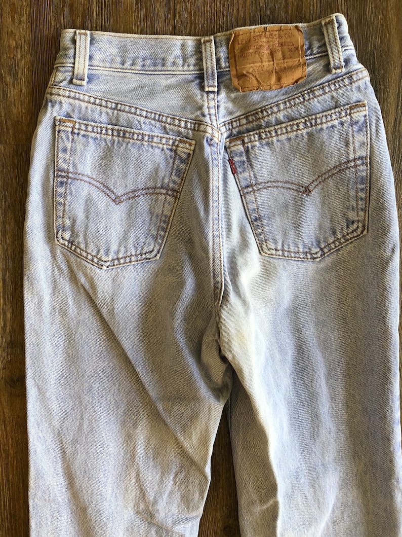 Puede incluir: Vaqueros de mezclilla azul claro con un parche de cuero marr&oacute;n Levi's en la parte posterior. Los vaqueros tienen cintura alta y pierna recta.