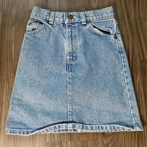 May include: A light blue denim mini skirt with a button closure and two front pockets.