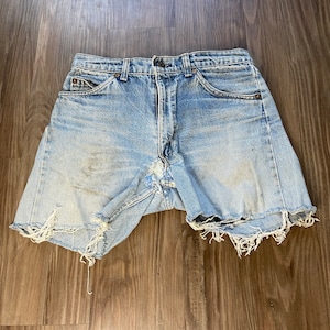 May include: Light blue denim shorts with frayed edges. The shorts have a high waist and five pockets.