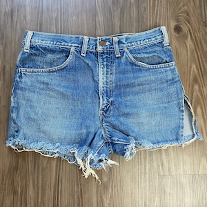 Puede incluir: Un short vaquero azul claro con dobladillo deshilachado y una abertura lateral. El short tiene cintura alta y un diseño clásico de cinco bolsillos.