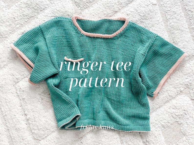 May include: A teal knitted ringer tee pattern with a pink trim around the neckline and sleeves. The text "ringer tee pattern" is written in white on the front of the shirt.