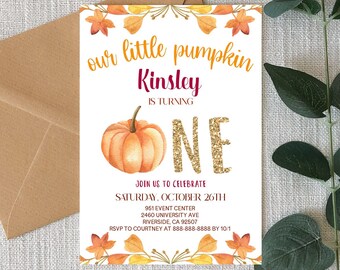 May include: A fall-themed invitation with the text "our little pumpkin Kinsley is turning ONE." The invitation features a watercolor pumpkin and autumn leaves. A brown envelope is visible in the background.