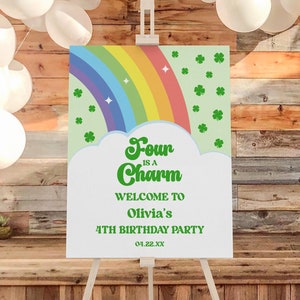 May include: A green and white welcome sign with a rainbow and shamrocks. The text reads "Four is a Charm, Welcome to Olivia's 4th Birthday Party, 01.22.XX".