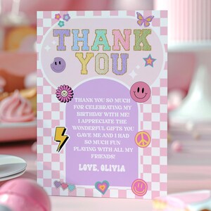 Könnte beinhalten: Eine rechteckige Dankeskarte mit einem hellrosa-weißen Karomuster am Rand, pastellfarbenem Text mit der Aufschrift THANK YOU und verschiedenen Symbolen wie einem Schmetterling, Smileys, einem Blitz und einem Friedenszeichen sowie dem Text LOVE, OLIVIA.