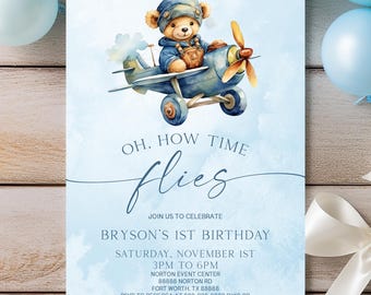 May include: A rectangular invitation card with a light blue watercolor background featuring a teddy bear pilot in a blue airplane. The text reads: OH, HOW TIME flies, JOIN US TO CELEBRATE, BRYSON'S 1ST BIRTHDAY, SATURDAY, NOVEMBER 1ST, 3PM TO 6PM, NORTON EVENT CENTER.