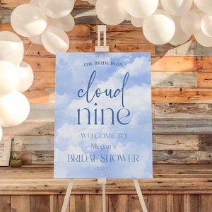 Può includere: Un cartello per la festa di addio al nubilato blu e bianco con il testo "The bride is on cloud nine. Welcome to Megan's Bridal Shower 01.22.XX".
