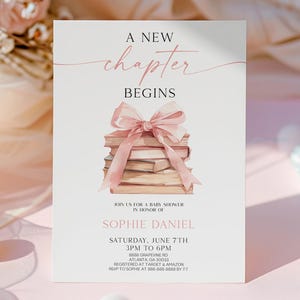 May include: A white card with pink text that reads "A New Chapter Begins". The card features a watercolor illustration of a stack of books tied with a pink ribbon. The card is a baby shower invitation for Sophie Daniel.