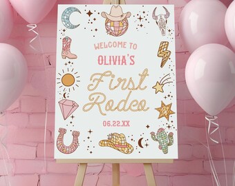 May include: A white rectangular sign on a wooden easel featuring the text Welcome to Olivia's First Rodeo 06.22.XX. The sign is decorated with illustrations of a cowboy hat, disco ball, moon, boot, sun, diamond, horseshoe, lightning bolt, star, and cactus.