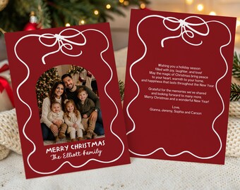 May include: Two rectangular Christmas cards with a deep red background and a white line-drawn bow at the top. The front card features a family photo in an arched frame with the text Merry Christmas The Elliott Family. The back card contains text.