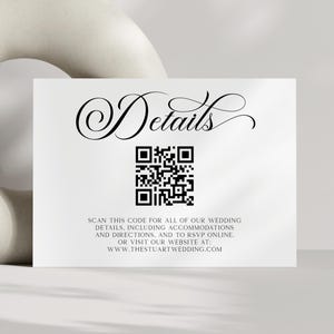 May include: A white card with the word "Details" in elegant script, a QR code, and text inviting guests to scan for wedding information. A cream-colored, abstract vase is in the background.