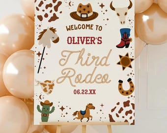 May include: A rectangular welcome sign on a wooden easel featuring the text Welcome to Oliver's Third Rodeo 06.22.XX. The sign is decorated with brown and white cow print, a cowboy hat, a bull skull, a boot, a star, a horseshoe, and a cactus.