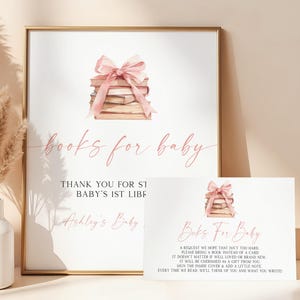 May include: A framed sign and card set with a baby shower theme. The sign and card feature a stack of books tied with a pink bow. The sign reads "books for baby" and includes text. The card also reads "Books For Baby" and includes text.