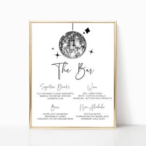 Puede incluir: Un menú de bar enmarcado con un borde dorado. El fondo blanco presenta un gráfico de bola de discoteca y las palabras "The Bar". Enumera bebidas de autor, vino, cerveza y bebidas sin alcohol. El texto está en una fuente elegante y manuscrita.
