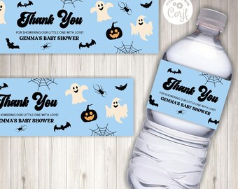 May include: A light blue water bottle label with Halloween-themed graphics. The label features a black "Thank You" message, bats, spiders, spiderwebs, ghosts, and a jack-o'-lantern. Text reads "FOR SHOWERING OUR LITTLE ONE WITH LOVE! GEMMA'S BABY SHOWER."