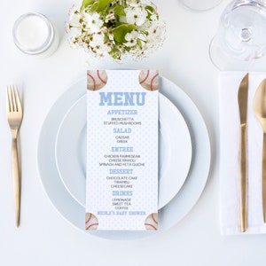 Puede incluir: Un menú de baby shower con temática de béisbol azul y blanco. El menú incluye aperitivos, ensalada, plato principal, postre y bebidas. El texto "Nicole's Baby Shower" está en la parte inferior del menú.