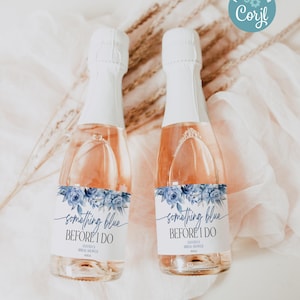 Op de afbeelding: Twee kleine flessen champagne met blauwe en witte etiketten waarop "something blue before I do" staat met een bloemmotief. De etiketten bevatten ook de tekst "Mandas Bridal Shower".