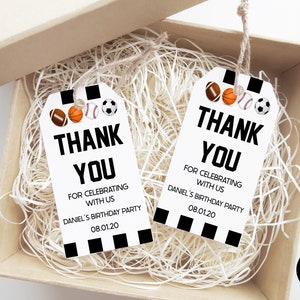 May include: Two white thank you gift tags with black and white stripes and a black border. The tags feature a variety of sports balls, including a football, basketball, baseball, and soccer ball. The text on the tags reads "Thank You" and "For Celebrating With Us Daniel's Birthday Party 08.01.20".