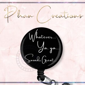 May include: Black retractable badge holder with a round, black button featuring white text that reads "Whatever... Ya, ya... Sounds Great..."