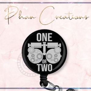 May include: Black and white eye chart with the text "ONE OR TWO" on a black retractable badge reel.