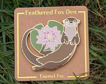 Pin de esmalte de nutria de río y loto