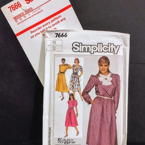 Puede incluir: Dos sobres de patrones de costura Simplicity. El sobre principal presenta un diseño de vestido con un estampado floral rosa, un lazo blanco y un cinturón. El sobre más pequeño muestra el número de patrón y las opciones de tallas. El texto "E-A-S-Y TO SEW" es visible.