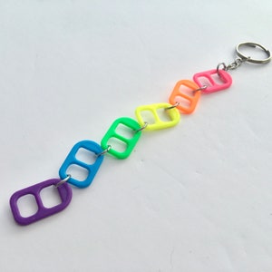 May include: A rainbow-colored keychain made from connected plastic rings. The keychain is attached to a silver key ring.