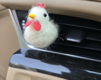 May include: A white felt chicken with a red comb and wattle, and a yellow beak. The chicken is an air vent accessory, designed to clip onto a car's air vent. The chicken is a decorative item.