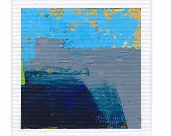 Puede incluir: Pintura abstracta con pintura azul, gris y dorada sobre un fondo blanco. La pintura está enmarcada en un passe-partout blanco.