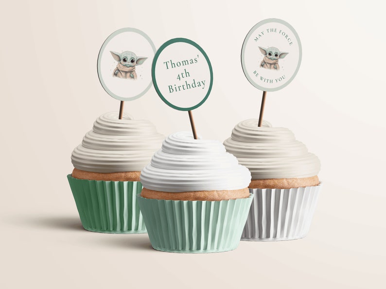 Pode incluir: Tr&ecirc;s cupcakes com cobertura verde e branca. Cada cupcake tem um topo de papel redondo, verde e branco com uma imagem de desenho animado de um personagem alien&iacute;gena verde. Os topos dizem "Que a for&ccedil;a esteja com voc&ecirc;", "Thomas' 4th Birthday", e uma imagem do personagem alien&iacute;gena.