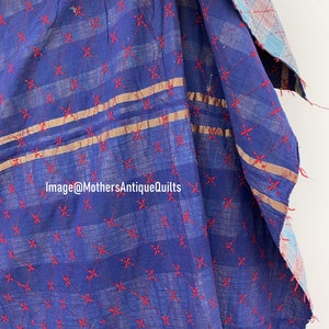 May include: A blue kantha quilt with red embroidered stars and two gold stripes. The quilt is folded and shows the back side, which is a plaid pattern.