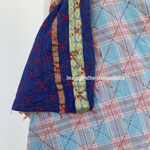 May include: A close-up of a blue and white kantha quilt with red stitching. The quilt has a gold and blue border with a floral pattern. The text "Image@MothersAntiqueQuilts" is visible in the lower right corner of the image.