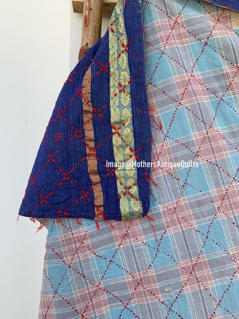 May include: A close-up of a blue and white kantha quilt with red stitching. The quilt has a gold and blue border with a floral pattern. The text "Image@MothersAntiqueQuilts" is visible in the lower right corner of the image.