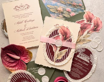 Könnte beinhalten: Ein Hochzeitspapeterie-Set mit cremefarbenen Karten mit Büttenrand, ovalen bordeauxroten Einlegern mit weißer Spitzenborte und einem grünen Umschlag mit Seerosenmotiv. Enthält ein rosa Band, weiße Wachssiegel und einen Ring in einer Samtschachtel.