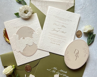 Könnte beinhalten: Ein Hochzeitseinladungs-Set mit olivgrünen Umschlägen, cremefarbenem Karton mit geprägten Blumenrändern und ovalen Einlegern. Der Text enthält die Namen Diana Antoun und Yousef Awad, ergänzt durch ein Wachssiegel und weiße Blumen.