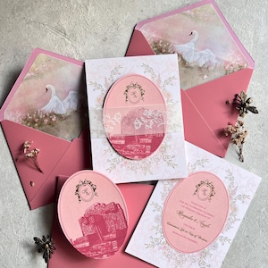 May include: Elegant wedding invitation suite in shades of pink and white. The set includes invitations, RSVP cards, and envelopes, adorned with floral patterns, swan illustrations, and a building graphic. The invitations feature the names "Ragaska & Angele".