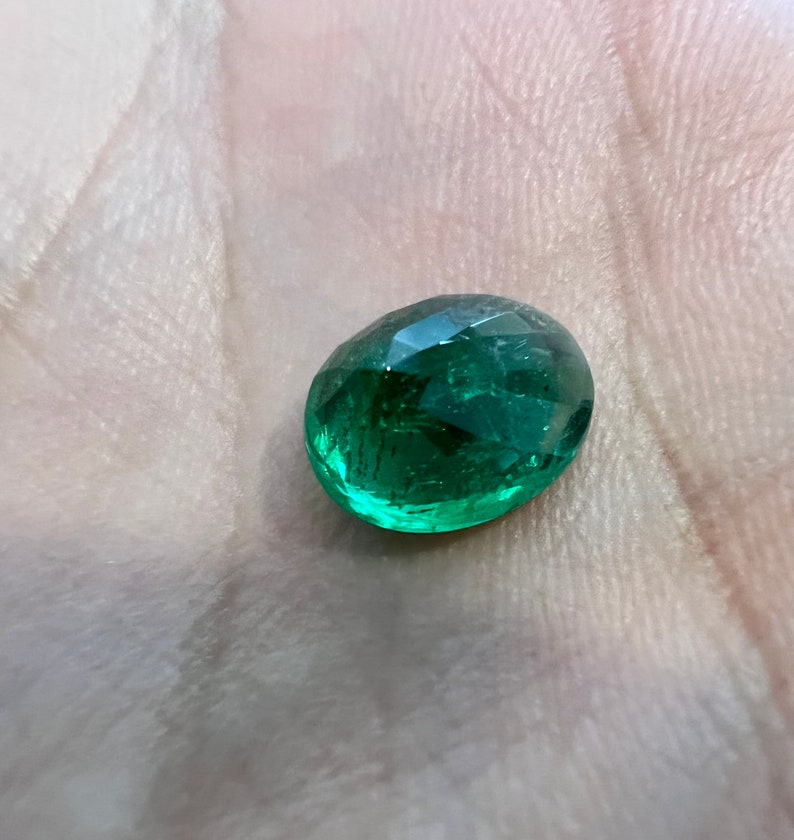 May include: A green oval-shaped gemstone with a faceted cut.