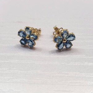 May include: A pair of gold flower-shaped earrings with blue gemstones.