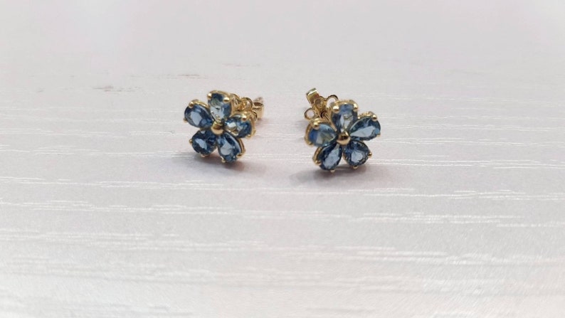 May include: A pair of gold flower-shaped earrings with blue gemstones.
