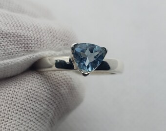 May include: A silver ring with a triangular blue gemstone.