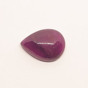 May include: A teardrop-shaped, faceted gemstone with a deep purple hue. The gemstone is polished and has a glossy finish.