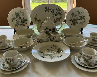 May include: A vintage tea set with a botanical design of green leaves and red berries. The set includes plates, bowls, cups, saucers, a teapot, sugar bowl, creamer, and serving platter. Silverware is also included.