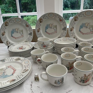 May include: A complete Peter Rabbit themed dinner service. The set includes plates, bowls, cups, and saucers, all decorated with illustrations of Peter Rabbit. The plates have a diameter of approximately 25 cm. A charming and complete set.